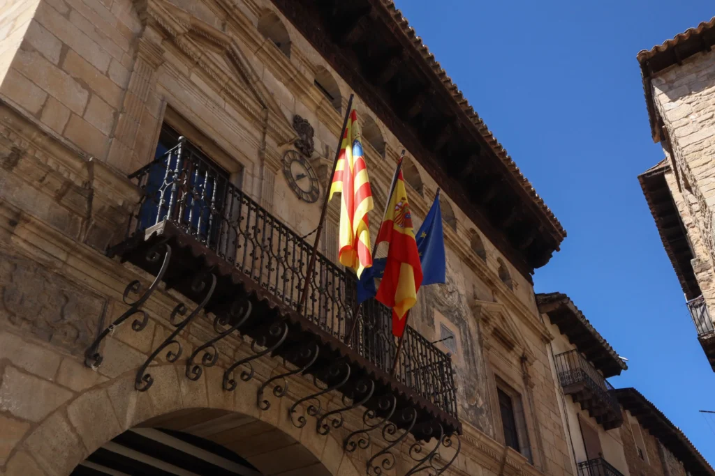 Fachada del Ayuntamiento de Valderrobres con balcones de forja y banderas en un edificio histórico del casco antiguo