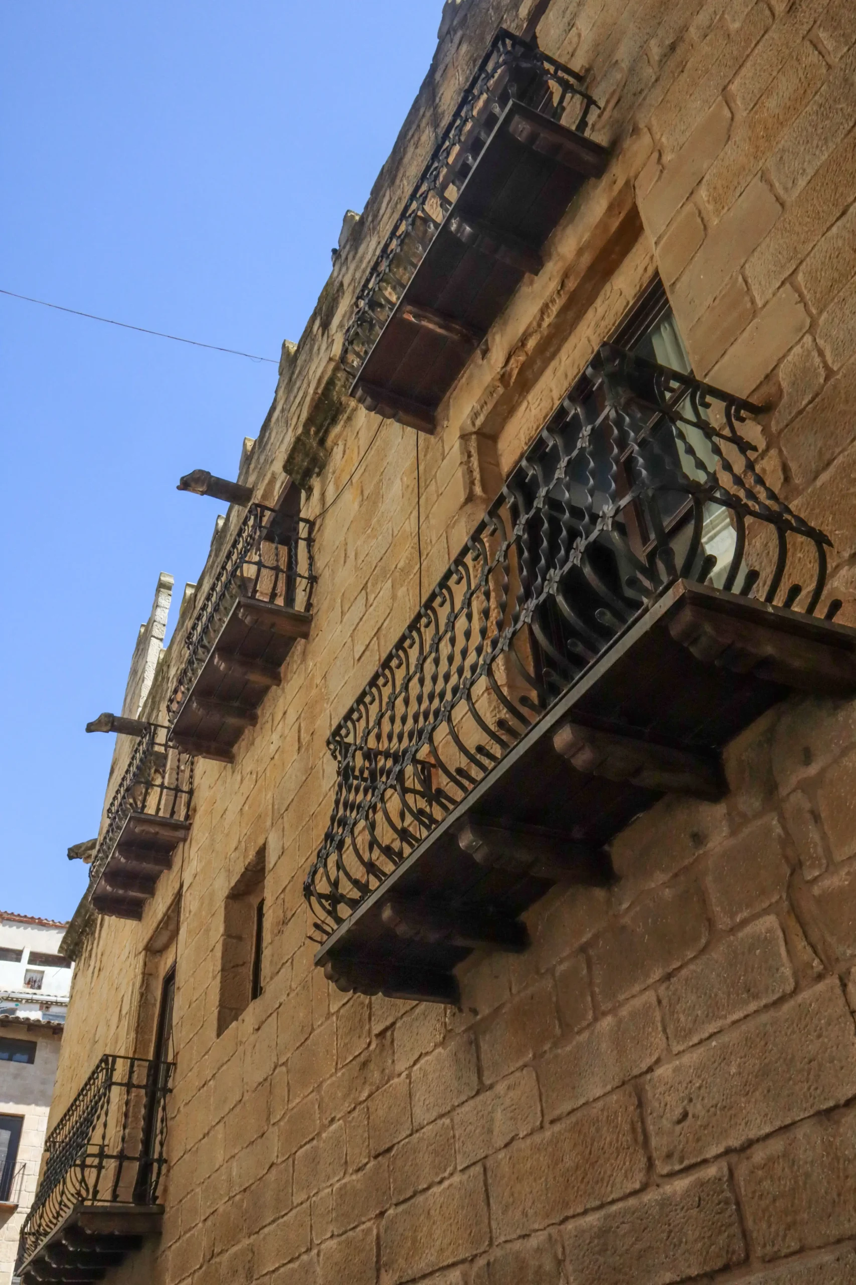 Detalle de balcones de hierro forjado en una fachada de piedra del casco histórico de Valderrobres con arquitectura tradicional