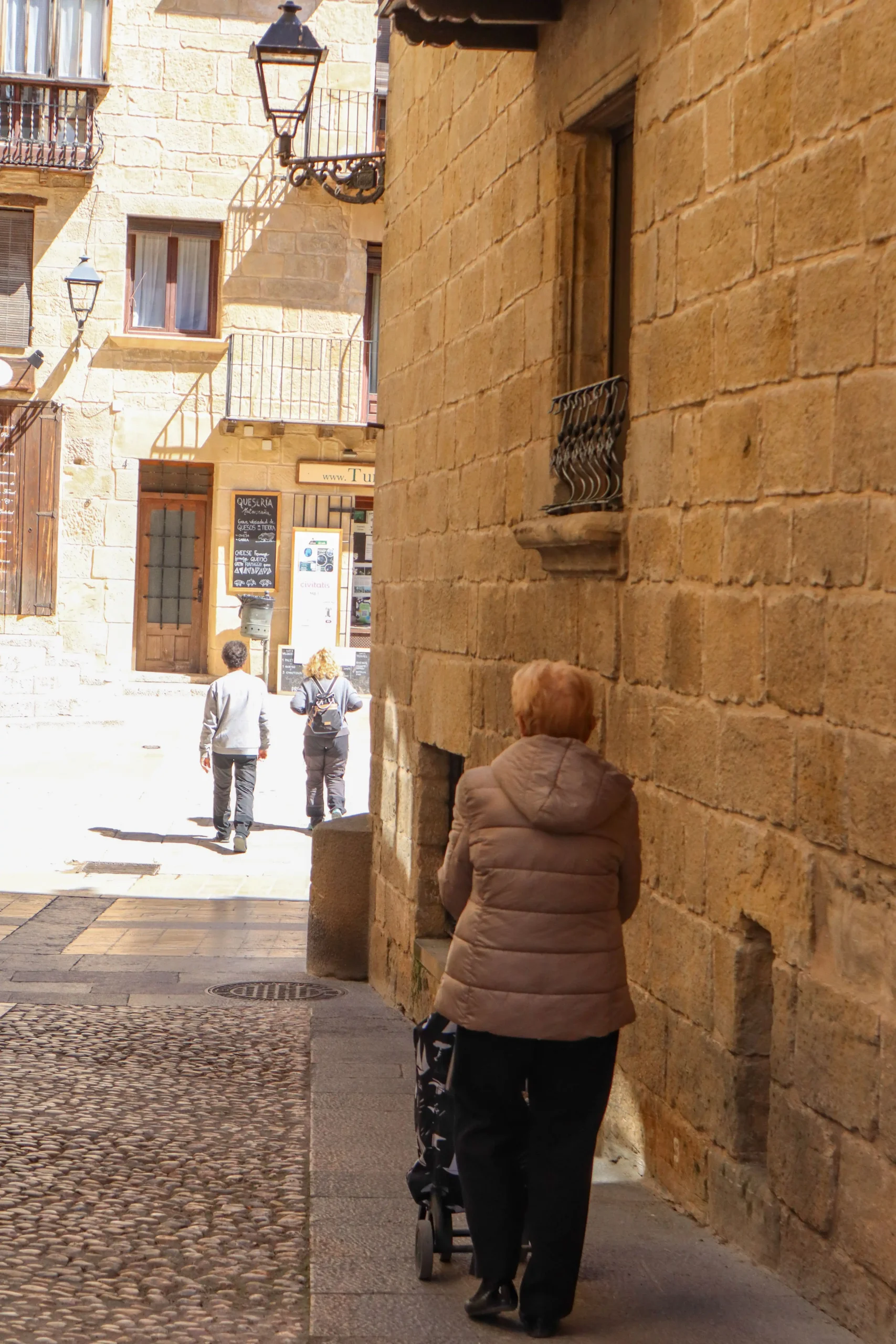 Persona caminando por una calle del casco histórico de Valderrobres con edificios de piedra y ambiente tranquilo del pueblo