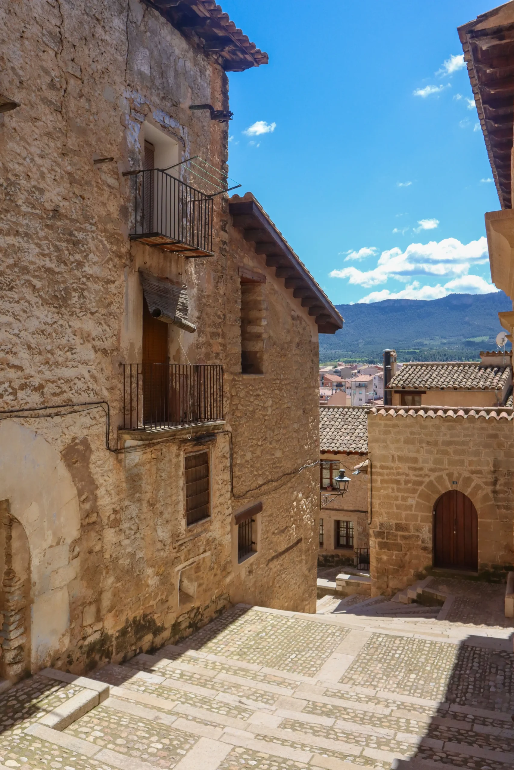 Calle del casco histórico de Valderrobres con casas de piedra y vistas al paisaje del Matarraña al fondo