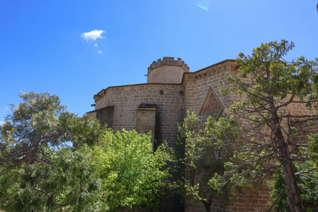 Vista exterior de la Iglesia de Santa María la Mayor de Valderrobres rodeada de árboles con arquitectura gótica en el casco histórico