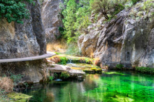 Pasarela sobre el agua en la ruta del Parrizal de Beceite rodeada de naturaleza y montañas