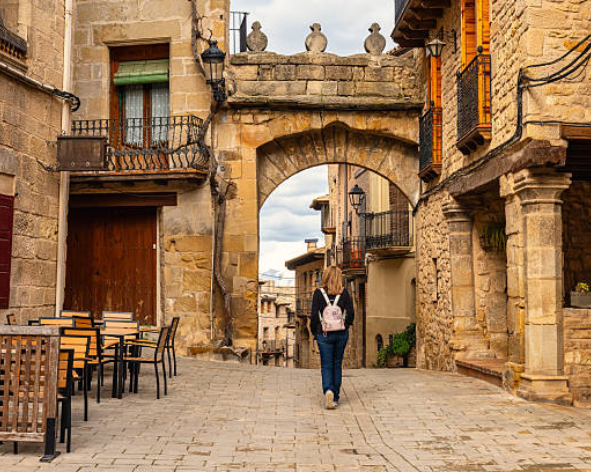 Persona paseando por una calle tradicional de un pueblo del Matarraña con arquitectura de piedra tradicional